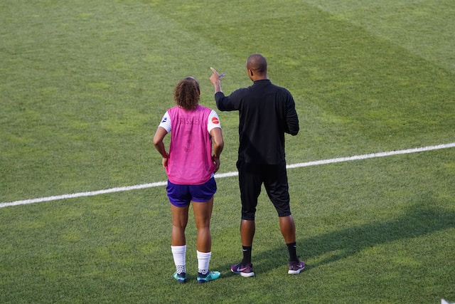 man coaching a woman on a football field